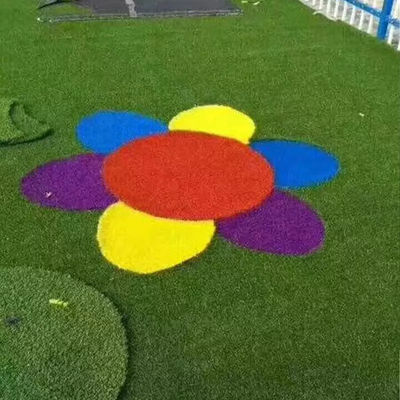 O arco-íris do campo de jogos do jardim de infância caçoa o relvado exterior vermelho